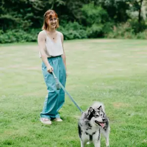 Juliette promenant Hoppy, pomsky gris et blanc, en laisse dans un parc