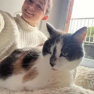 Selfie de Juliette avec Pipou, chat tricolore couché sur un plaid près de la fenêtre