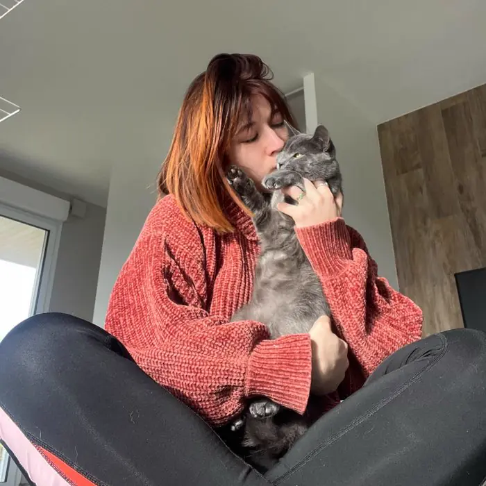 Femme câlinant un chat gris assis sur ses genoux
