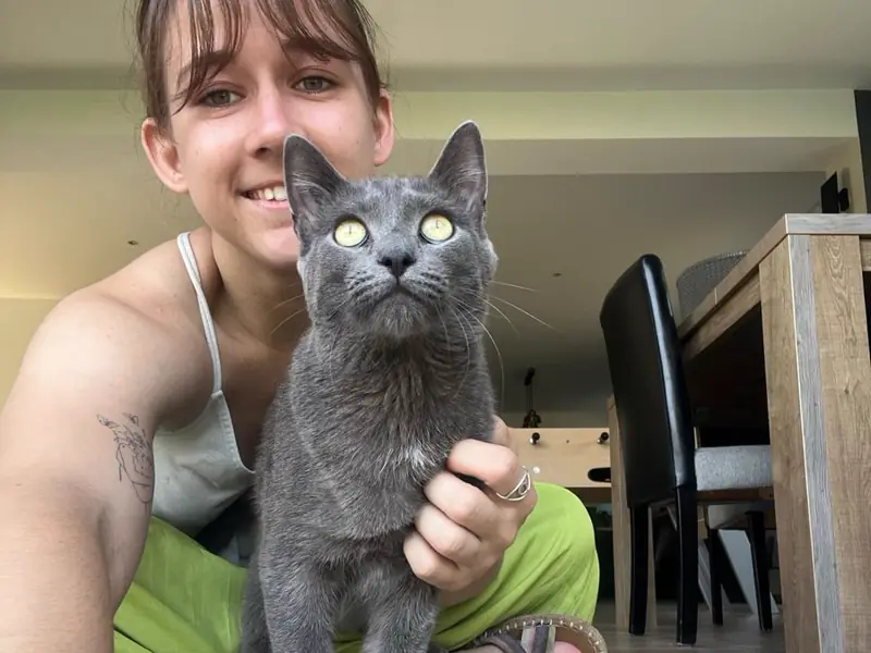 Juliette tenant un chat gris dans ses bras, à l'intérieur de la maison